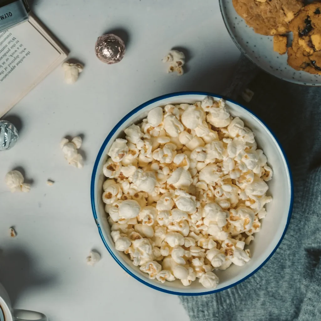 Uma tigela de cerâmica cheia de pipoca estourada e salpicada com flocos de levedura nutricional fina